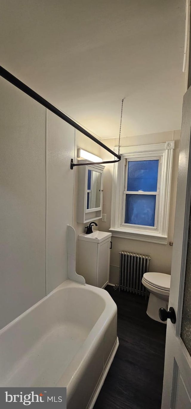 full bath featuring toilet, radiator heating unit, wood finished floors, and vanity