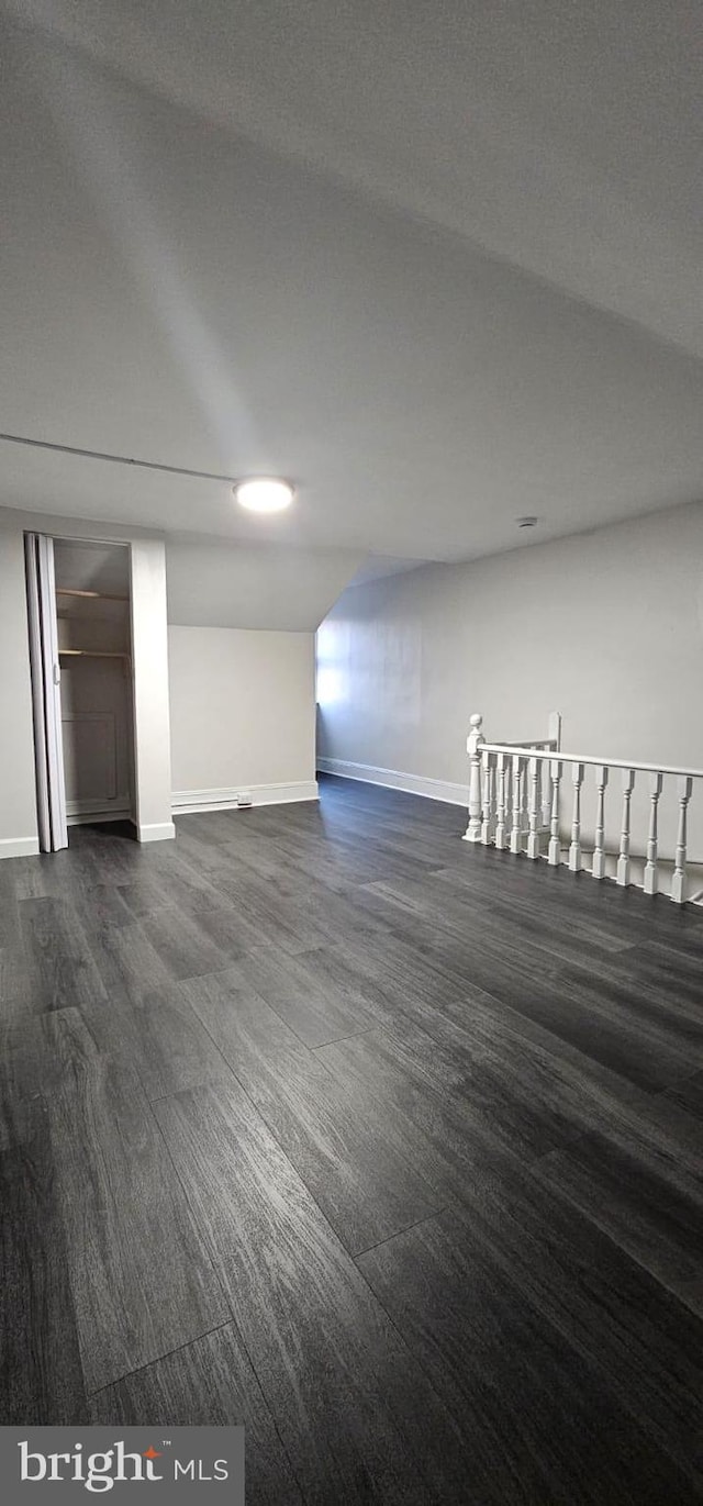 interior space featuring a textured ceiling, dark wood-style flooring, and baseboards