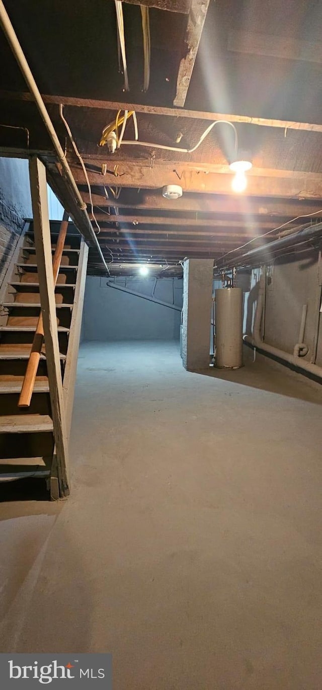 unfinished below grade area featuring stairs and gas water heater