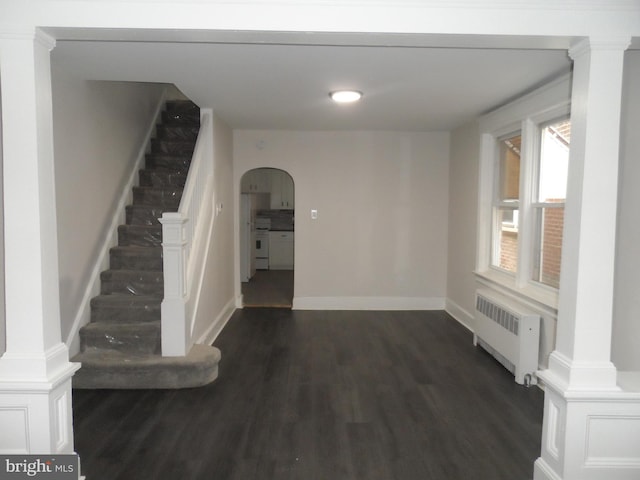 interior space featuring arched walkways, stairway, dark wood finished floors, and radiator