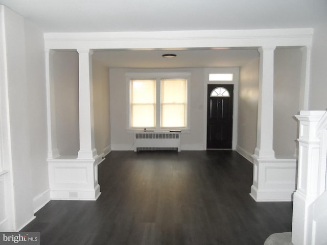 foyer with decorative columns, a wainscoted wall, radiator heating unit, dark wood-style flooring, and a decorative wall