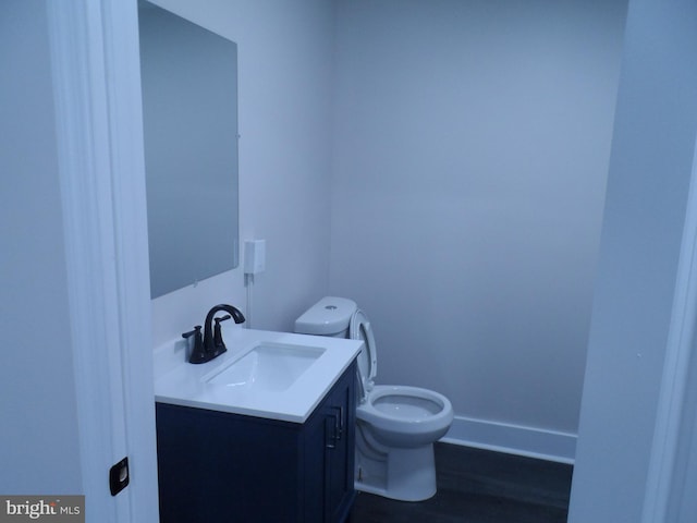 half bath with toilet, baseboards, and vanity