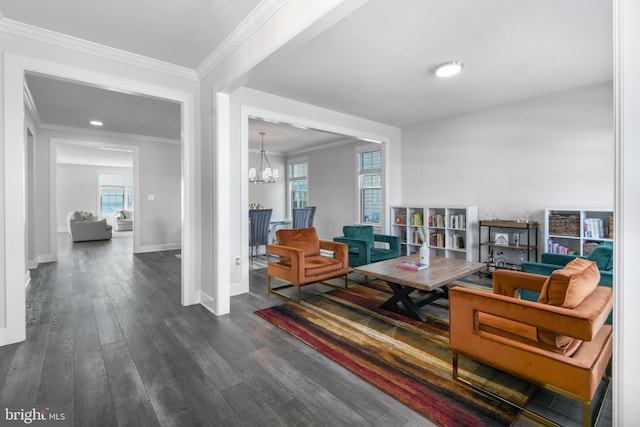 living area with baseboards, ornamental molding, wood finished floors, and a notable chandelier