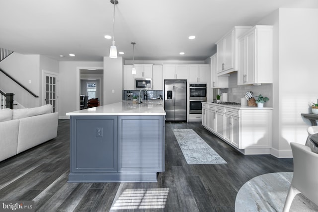 kitchen with backsplash, appliances with stainless steel finishes, open floor plan, and a sink