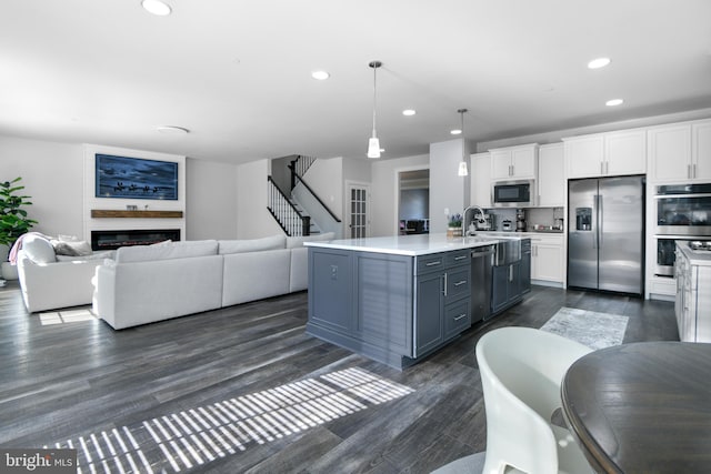 kitchen with white cabinets, stainless steel appliances, light countertops, and open floor plan