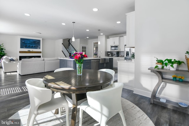 dining area with recessed lighting, a fireplace, baseboards, stairway, and dark wood-style floors