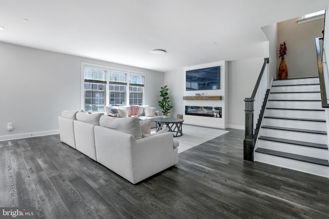 living room with dark wood-style floors, stairs, baseboards, and a glass covered fireplace