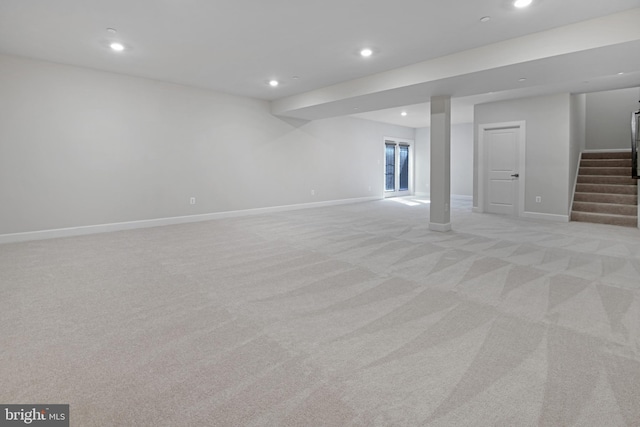 below grade area featuring recessed lighting, light carpet, baseboards, and stairs