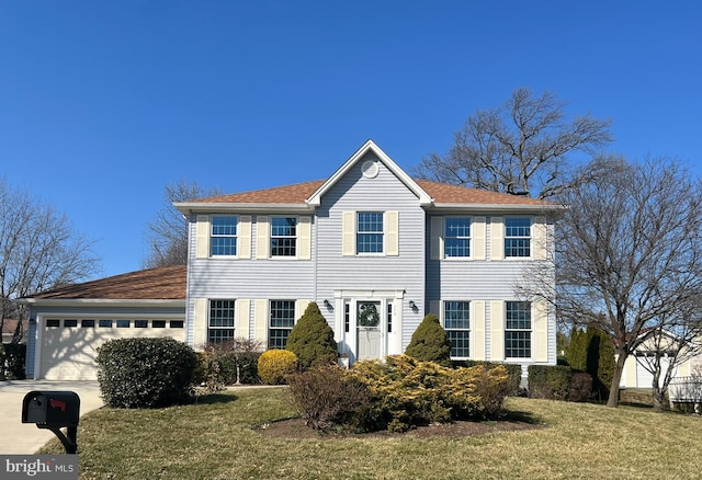 colonial inspired home with concrete driveway, a front lawn, and an attached garage