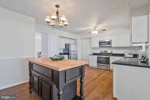 kitchen with white cabinets, light wood finished floors, wood counters, and stainless steel appliances