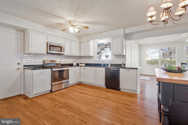 kitchen featuring appliances with stainless steel finishes, white cabinetry, light wood-style flooring, and ceiling fan with notable chandelier