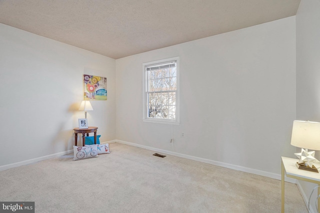 interior space featuring baseboards, visible vents, a textured ceiling, and carpet flooring