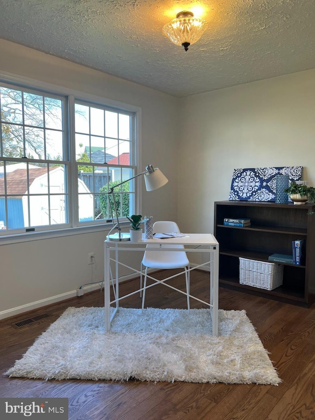 office area featuring visible vents, a textured ceiling, baseboards, and wood finished floors