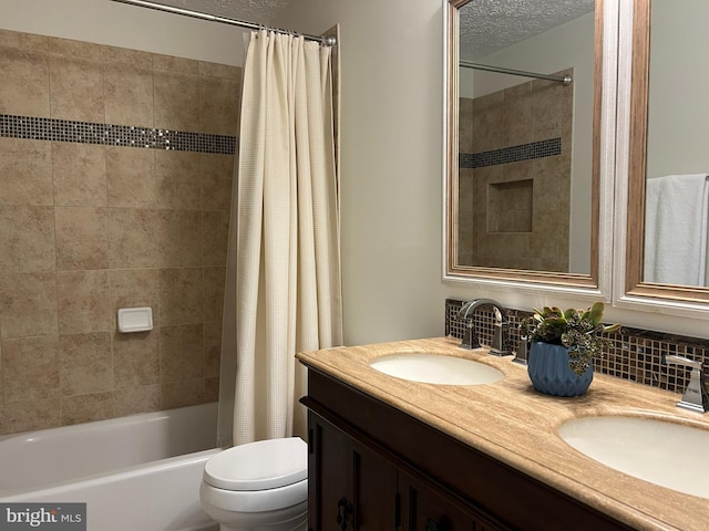 bathroom featuring toilet, double vanity, a textured ceiling, and a sink