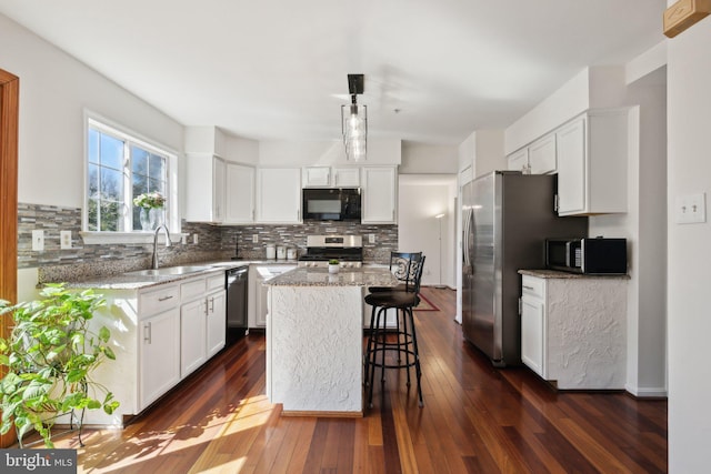 kitchen featuring a kitchen island, a sink, white cabinets, appliances with stainless steel finishes, and dark wood finished floors