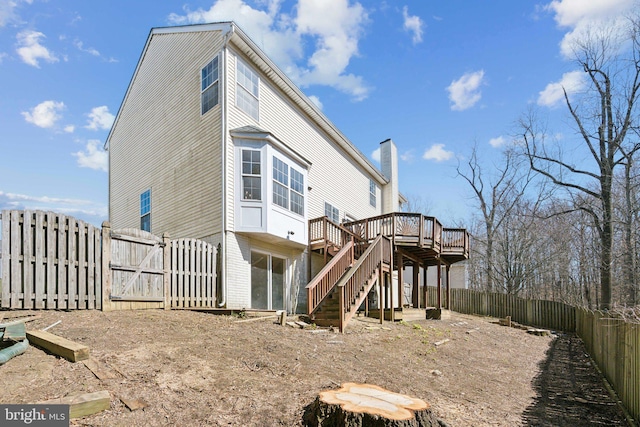 rear view of property featuring a deck, a fenced backyard, brick siding, stairway, and a gate