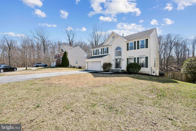 view of front facade with a garage, concrete driveway, a front yard, and fence