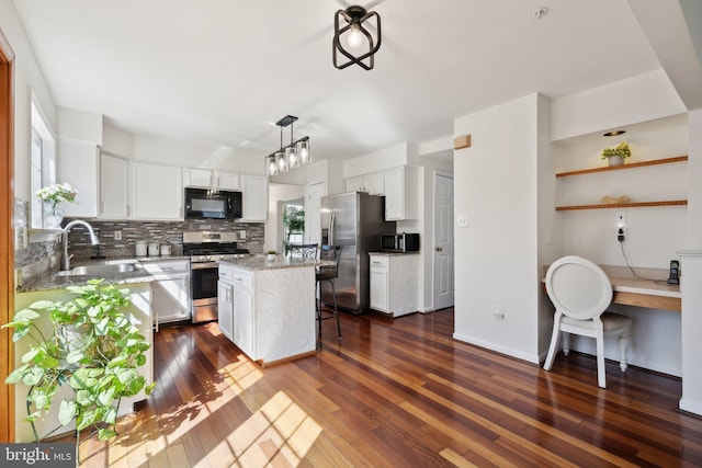 kitchen with dark wood-style flooring, backsplash, appliances with stainless steel finishes, white cabinets, and a sink