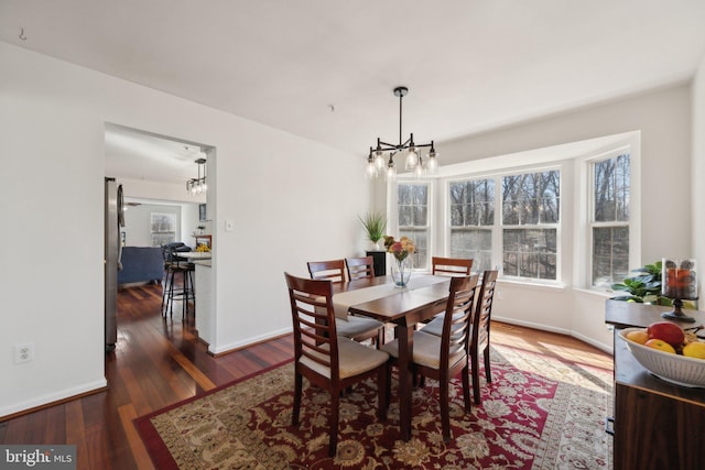 dining area with a notable chandelier, baseboards, and hardwood / wood-style flooring