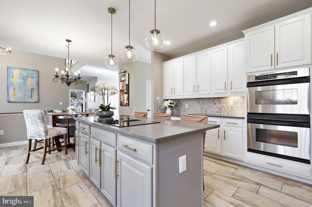 kitchen featuring tasteful backsplash, a kitchen island, black electric stovetop, double oven, and white cabinets