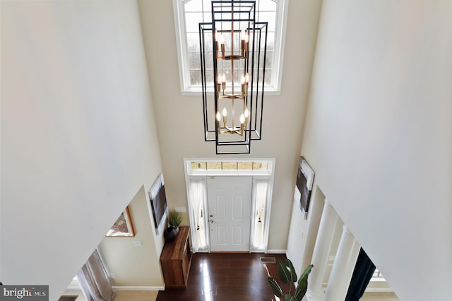 entrance foyer featuring wood finished floors, visible vents, a towering ceiling, and baseboards