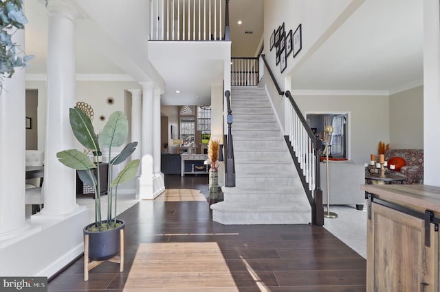 foyer with stairway, ornamental molding, ornate columns, and wood finished floors