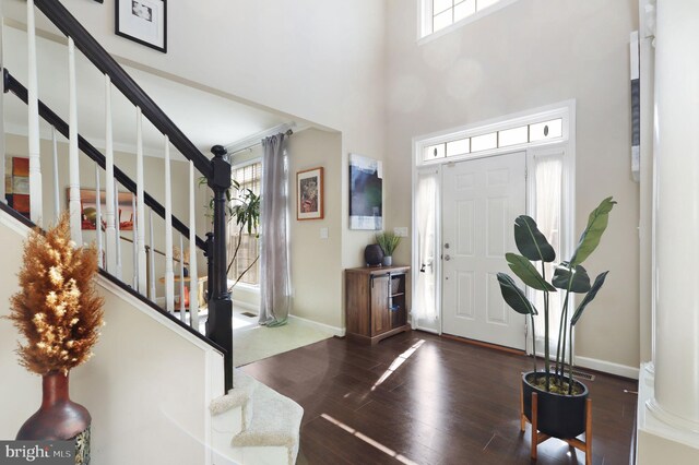 foyer with a wealth of natural light, stairs, baseboards, and wood finished floors