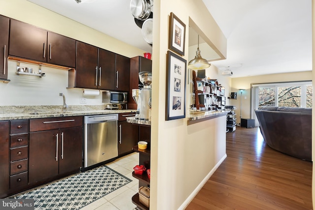 kitchen featuring a sink, open floor plan, dark brown cabinets, appliances with stainless steel finishes, and light wood-type flooring