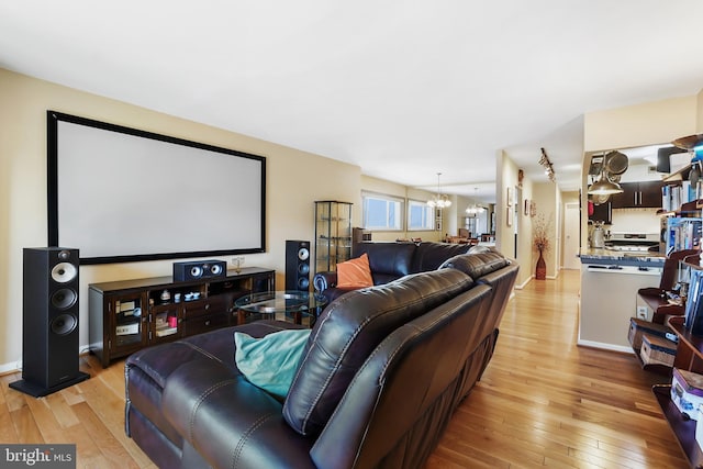 home theater with light wood-style floors and an inviting chandelier