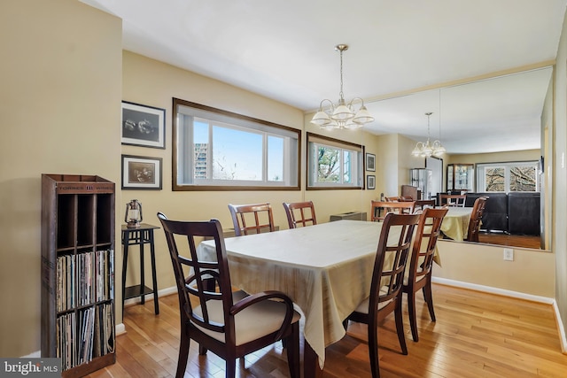 dining room with a notable chandelier, baseboards, and light wood-style floors