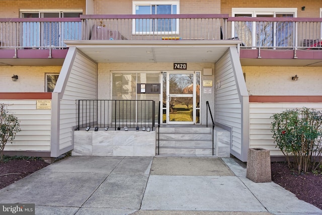 doorway to property featuring a balcony and brick siding