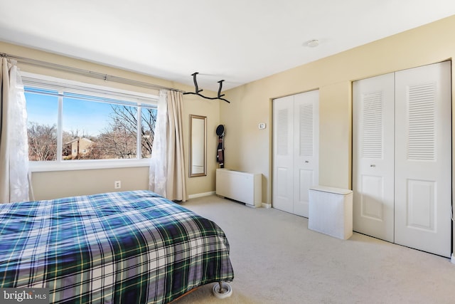 bedroom with two closets, baseboards, and carpet floors