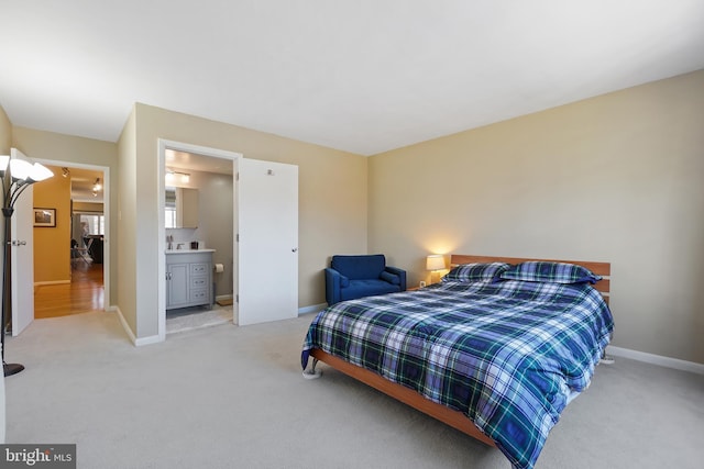 bedroom featuring light carpet, ensuite bath, and baseboards