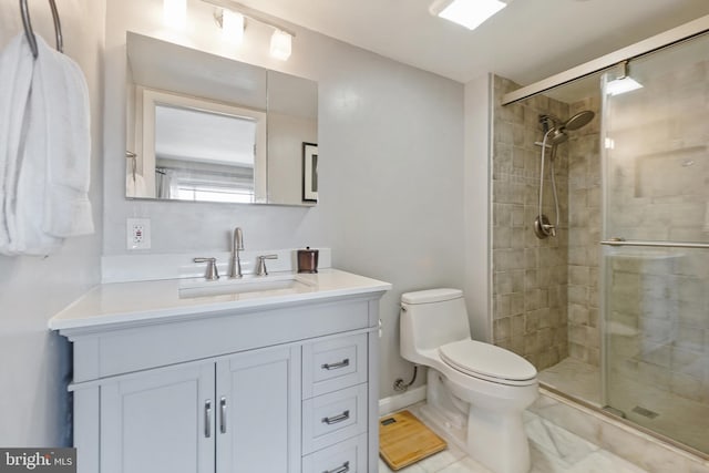 full bathroom featuring vanity, a shower stall, toilet, and baseboards