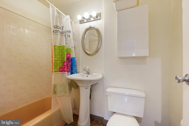 bathroom featuring toilet, shower / bath combo, and a sink