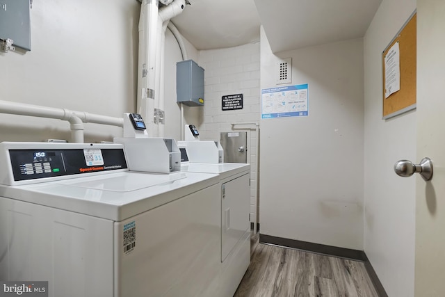 community laundry room with baseboards, independent washer and dryer, and wood finished floors