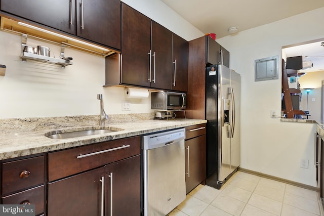 kitchen featuring light tile patterned floors, baseboards, a sink, dark brown cabinetry, and appliances with stainless steel finishes