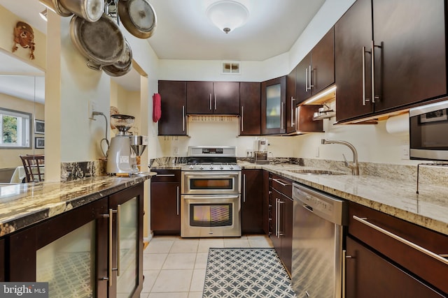 kitchen with visible vents, a sink, light stone counters, stainless steel appliances, and wine cooler