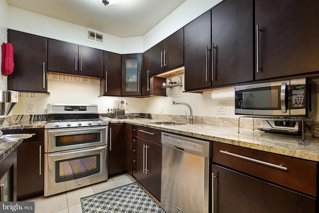 kitchen featuring visible vents, light stone countertops, light tile patterned floors, appliances with stainless steel finishes, and a sink