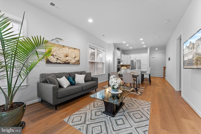 living room featuring light wood finished floors, baseboards, visible vents, and recessed lighting