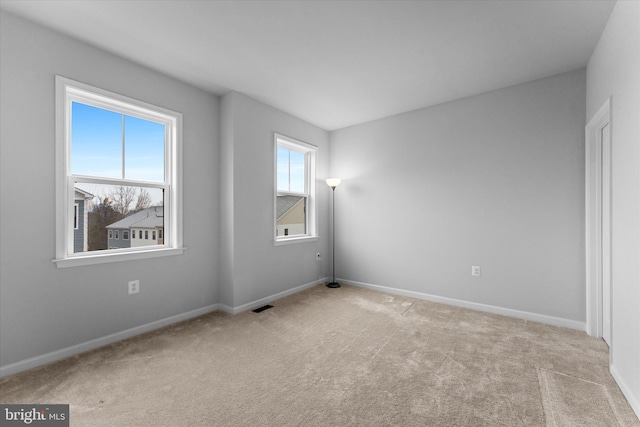 carpeted empty room featuring visible vents and baseboards