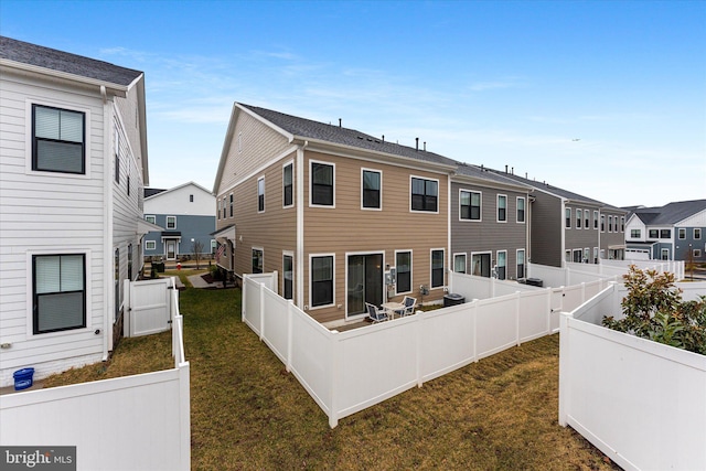 rear view of house featuring a fenced backyard, a residential view, and a lawn