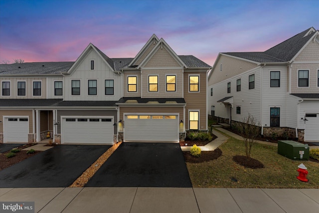 multi unit property featuring driveway, stone siding, a garage, and board and batten siding