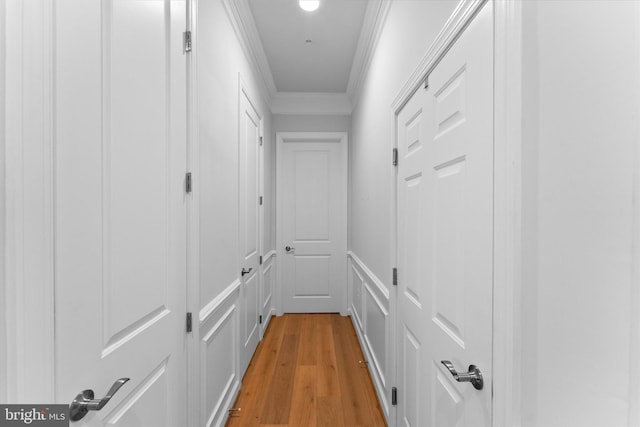 hall with ornamental molding and light wood-style floors