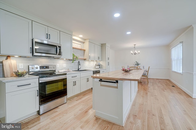 kitchen with butcher block countertops, light wood-style flooring, appliances with stainless steel finishes, and a sink