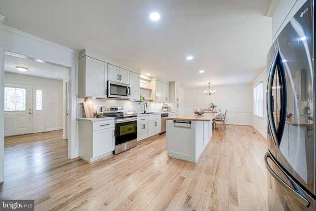 kitchen with a sink, light wood-type flooring, butcher block countertops, and appliances with stainless steel finishes