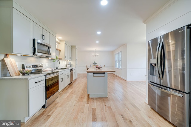 kitchen featuring light wood-type flooring, a notable chandelier, a sink, backsplash, and stainless steel appliances