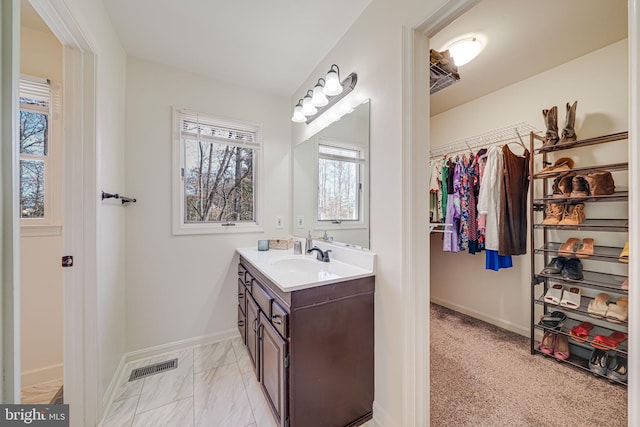 bathroom featuring visible vents, marble finish floor, vanity, baseboards, and a spacious closet