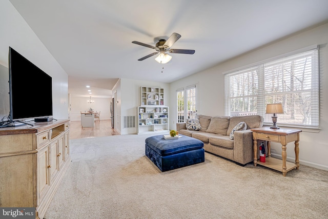 living area featuring a ceiling fan, light colored carpet, and baseboards