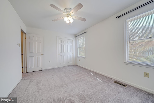 unfurnished bedroom featuring visible vents, a closet, carpet, baseboards, and ceiling fan